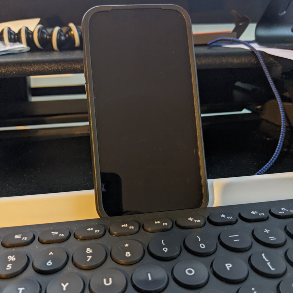 iPhone 12 Mini in OtterBox Symmetry Case sitting comfortably in the notch of the Logitech K780 keyboard